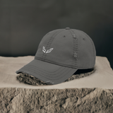 Velite Armor distressed cotton dad hat in charcoal gray with embroidered logo, displayed on a textured surface for a premium aesthetic.