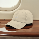 Velite Armor Premium Distressed Hat in beige, embroidered logo, placed inside a private jet for a sophisticated, high-end luxury aesthetic