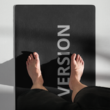 Close-up of a person’s feet standing on a Velite Armor black yoga mat with partial text “Version” visible, emphasizing mindfulness and stability.