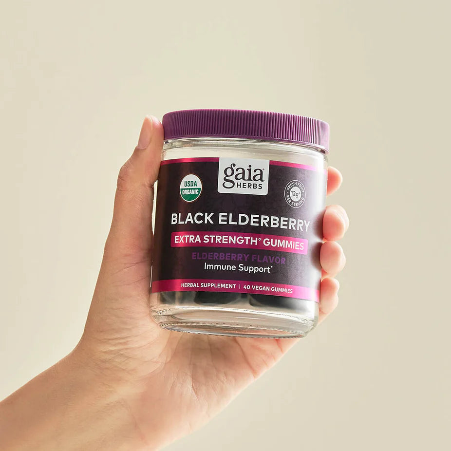 Hand holding a jar of Black Elderberry Extra Strength Gummies - 120 ct (COG), emphasizing its convenient size and immune support benefits.