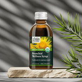 Organic Bronchial Herbal Syrup bottle next to green plant, highlighting natural formula

