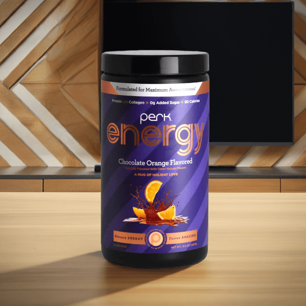 Perk Energy Chocolate Orange-Boost Drink, 20 servings, shown indoors on a wooden table with TV background, ideal for daily energy support.