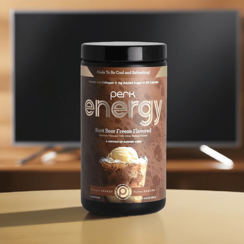 Perk Energy Root Beer Freeze Drink on a table with TV background, featuring 20 servings of creamy, low-calorie energy and immune support blend.