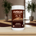 Evolve Protein Powder Classic Chocolate 1 lb tub on wooden table with indoor plants, plant-based protein