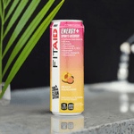 FitAid Energy Peach Mandarin can next to a shaker bottle and palm leaf, styled for a fitness vibe.

