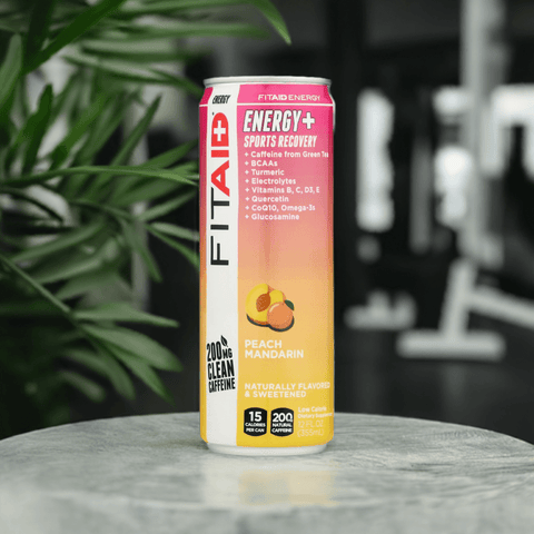 Front view of FitAid Energy Peach Mandarin can on a countertop with greenery in the background.

