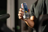 Man drinking a can of FitAid Energy Blackberry Pineapple while sitting in a gym setting.