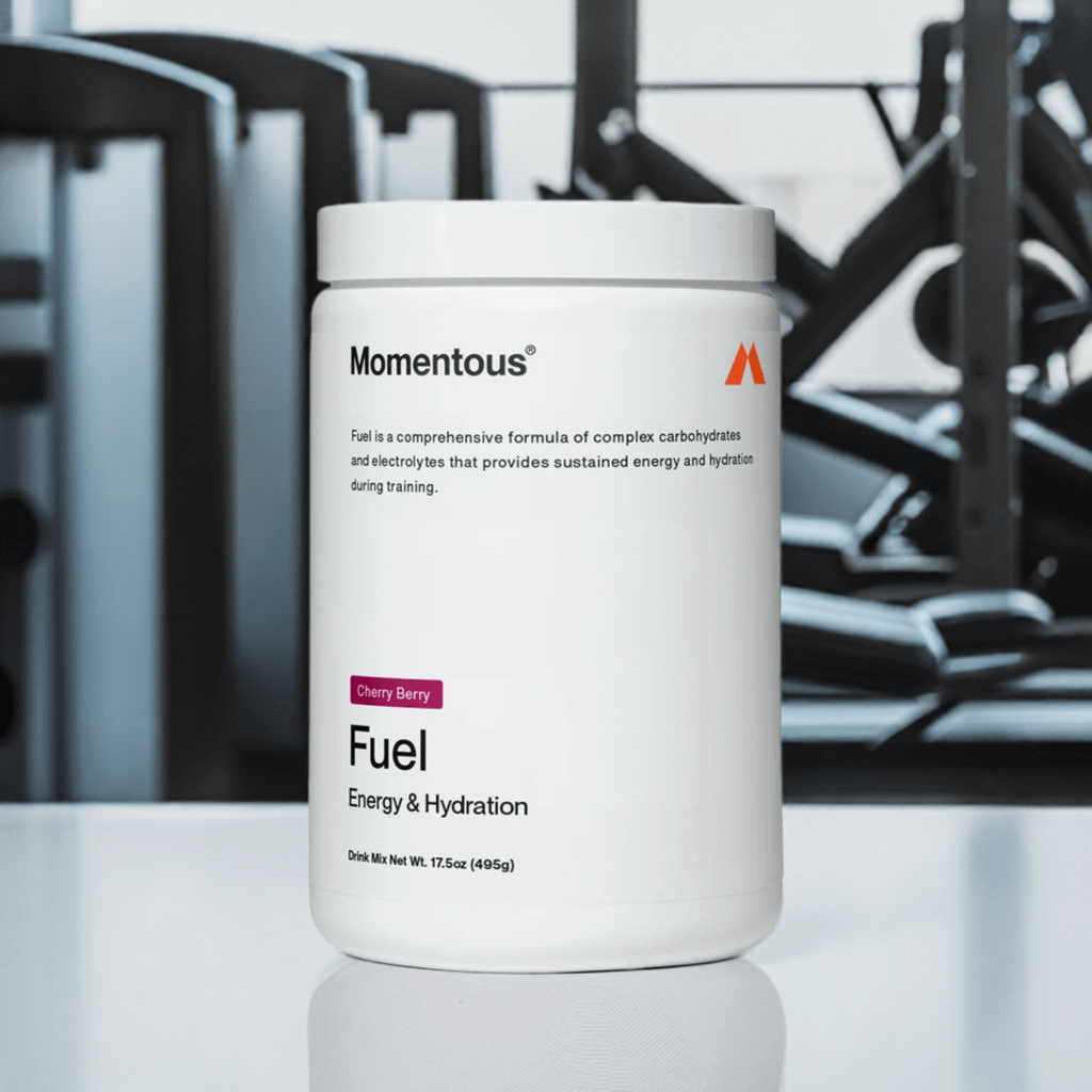 Fuel - Momentous - Cherry Berry - Energy Hydration supplement with electrolytes and carbs for workouts over 60 minutes, shown in gym setting.