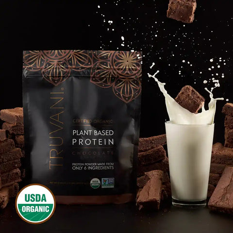 Truvani Organic Chocolate Brownie Batter Protein powder pouch on a dark table next to a glass of milk with a splash, USDA Organic certified.