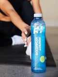 Athlete tying shoelaces while holding Perfect Hydration Alkaline Water 1L bottle with pH 9.5+, ideal for fitness and recovery hydration.

