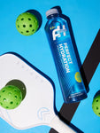 Perfect Hydration Alkaline Water 1L bottle with pH 9.5+, shown next to pickleball paddles for active lifestyle hydration.

