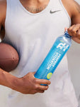 Man holding Perfect Hydration Alkaline Water 1L bottle, pH 9.5+, electrolyte-enriched water for workout hydration.

