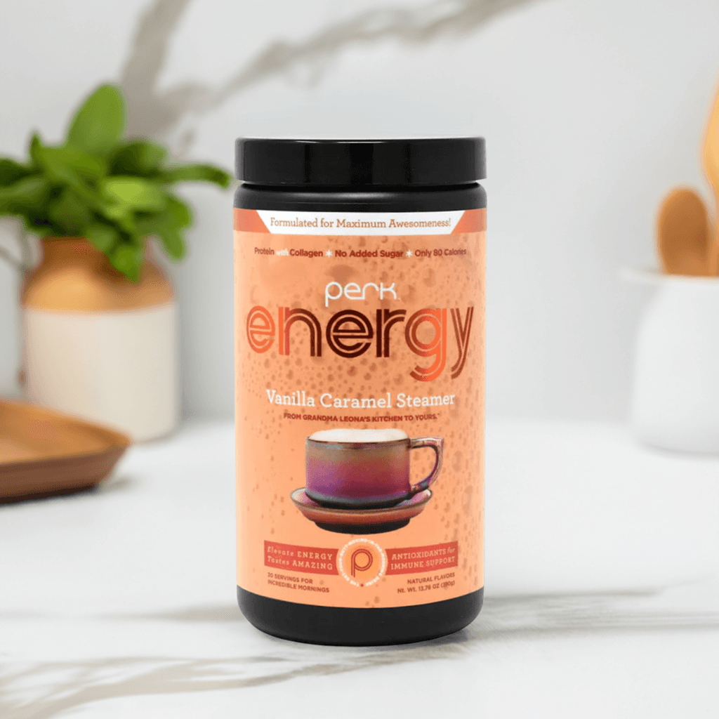 Perk Energy Vanilla Caramel Steamer in a sleek black-lid container, featuring an inviting caramel-colored label with a warm coffee cup illustration, set against a bright kitchen backdrop with wooden and ceramic elements.