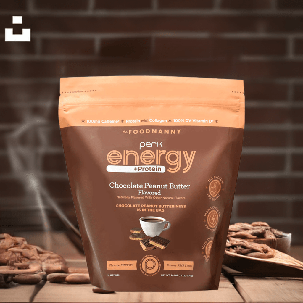 Perk Energy + Protein – Chocolate Peanut Butter pouch placed on a wooden surface with a rustic brick wall background, accompanied by pecans and a steaming effect for a warm, cozy feel.
