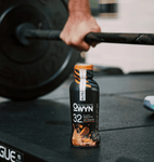 Athlete holding OWYN 35g Chocolate Peanut Butter Protein Shake post-workout – vegan, clean fuel for muscle recovery.