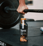 Athlete holding OWYN 35g Chocolate Peanut Butter Protein Shake post-workout – vegan, clean fuel for muscle recovery.