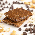 Close-up of Probar Oatmeal Chocolate Chip bar surrounded by oats and chocolate chips, healthy plant-based meal option