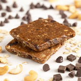 Close-up of Probar Oatmeal Chocolate Chip bar surrounded by oats and chocolate chips, healthy plant-based meal option