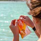 Woman enjoying Probar Banana Nut Bread bar by the poolside, healthy snack for outdoor lifestyles