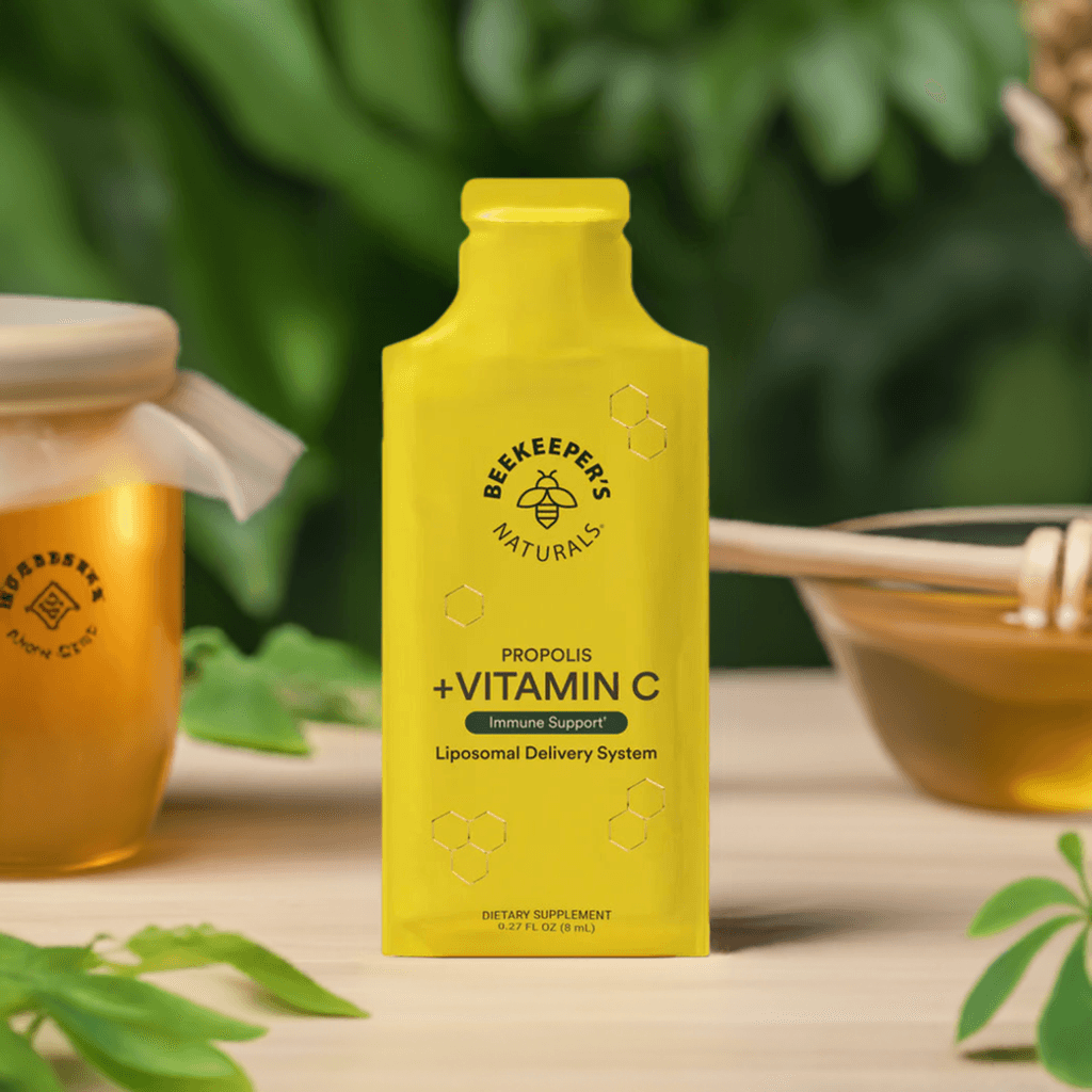 Propolis + Vitamin C Liposomal by Beekeeper's Naturals in a bright yellow bottle, designed for immune support and enhanced absorption. Surrounded by honey and greenery, ideal for health-conscious consumers seeking high-potency multivitamin supplements.
