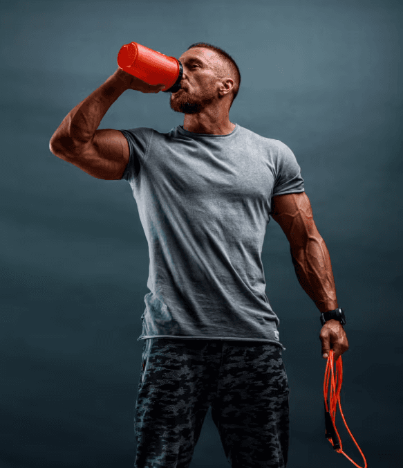 Man drinking from a shaker bottle holding a jump rope