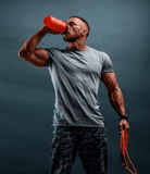 Man drinking from a shaker bottle holding a jump rope