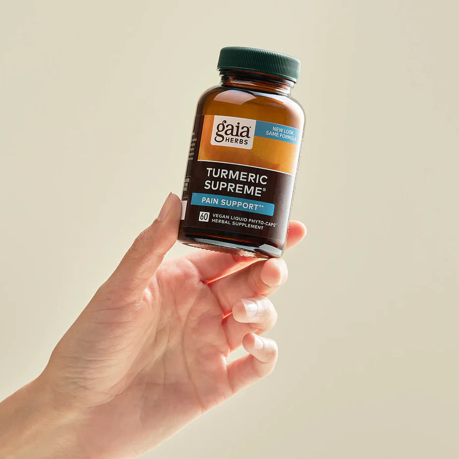 Hand holding Gaia Herbs Turmeric Supreme® Pain - ACTIVE LIFESTYLE supplement bottle, showcasing vegan capsules for joint and muscle pain relief.