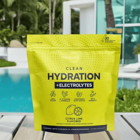 Citrus Lime Clean Hydration + Electrolytes pouch on a poolside table with tropical greenery and a luxury house in the background.