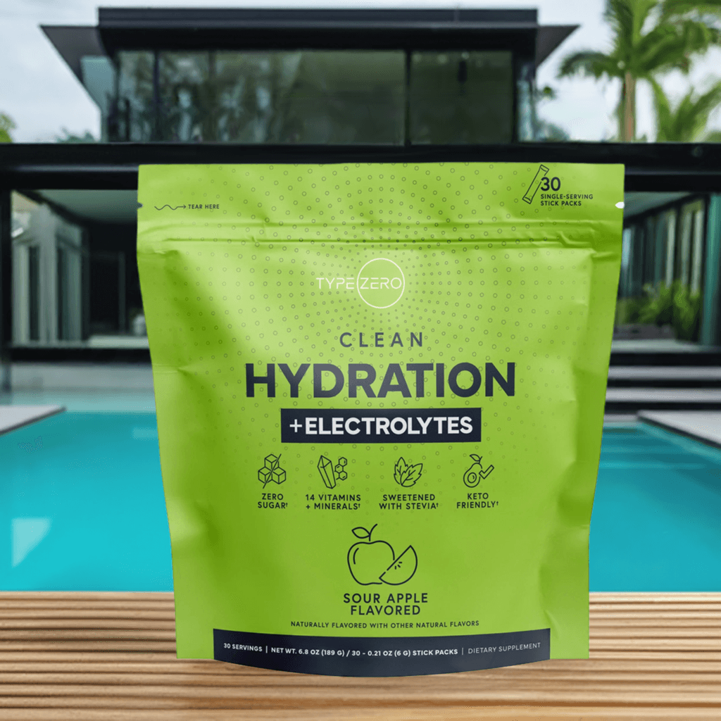 Clean Hydration + Electrolytes pouch displayed poolside with a sleek black glass-front house and tropical plants behind it, emphasizing a luxurious healthy lifestyle.