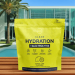 Front-facing Citrus Lime hydration pack with bright yellow packaging, placed poolside on a sunny day next to a luxury villa.