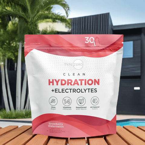 Type Zero Clean Hydration + Electrolytes, Strawberry Watermelon flavor, dietary supplement with zero sugar, 14 vitamins and minerals, sweetened with stevia and natural colors. Displayed on a wooden surface near a pool with a modern black house and palm trees in the background. 