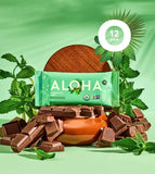 Aloha Chocolate Mint Protein Bar 12-pack surrounded by dark chocolate pieces and fresh mint leaves on a green background. USDA Organic, Non-GMO, and vegan certified snack.