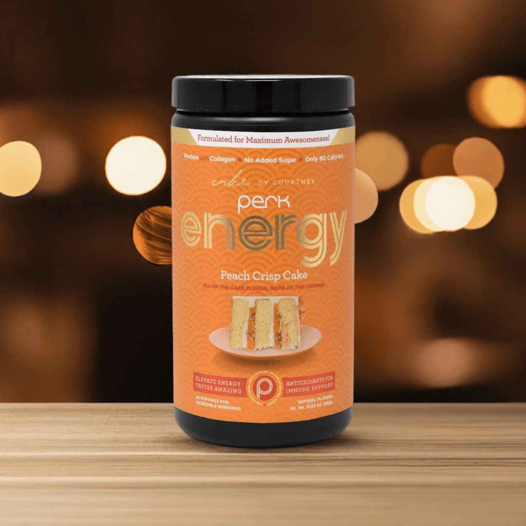 Perk Energy Original Peach Crisp Cake drink mix in orange container on wooden surface, featuring 20 servings of gourmet energy blend with collagen and protein.