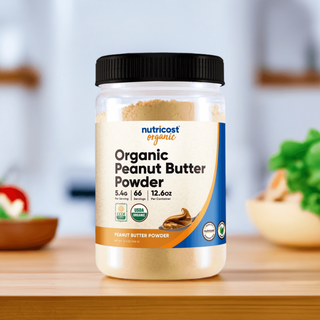Nutricost Organic Peanut Butter Powder jar on kitchen counter, featuring 6g protein, no added sugars, and USDA Organic certification.
