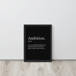 Framed inspirational wall print with the word "Ambition" placed on the floor against a white wall in a minimalist room.