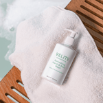 Velite Essentials Citrus Fresh Body Wash placed on a towel by a bath, perfect for daily moisturizing and gentle cleansing in a spa-like setting.