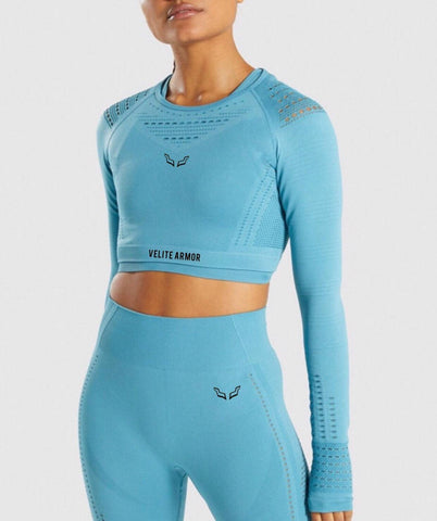 Light blue seamless long-sleeve cropped top and high-waisted leggings set from Velite Armor, ideal for fitness and training. Featuring subtle mesh details and branding logos for style and comfort. / Conjunto celeste de top corto manga larga sin costuras y leggings de talle alto de Velite Armor, ideal para fitness y entrenamientos. Incluye detalles sutiles de malla y logotipos de la marca para estilo y comodidad.