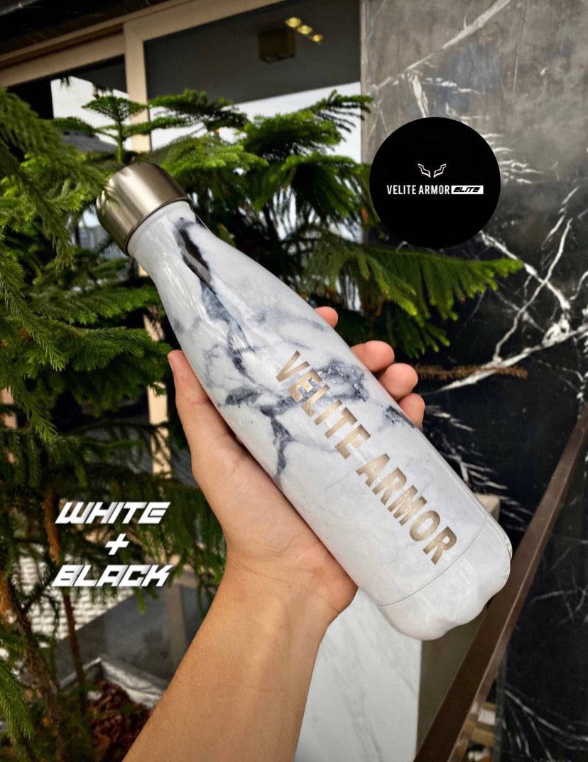 Velite Armor (ELITE) Water Bottle 17oz in white and black marble, stylish stainless steel accessory shown with greenery and stone wall.