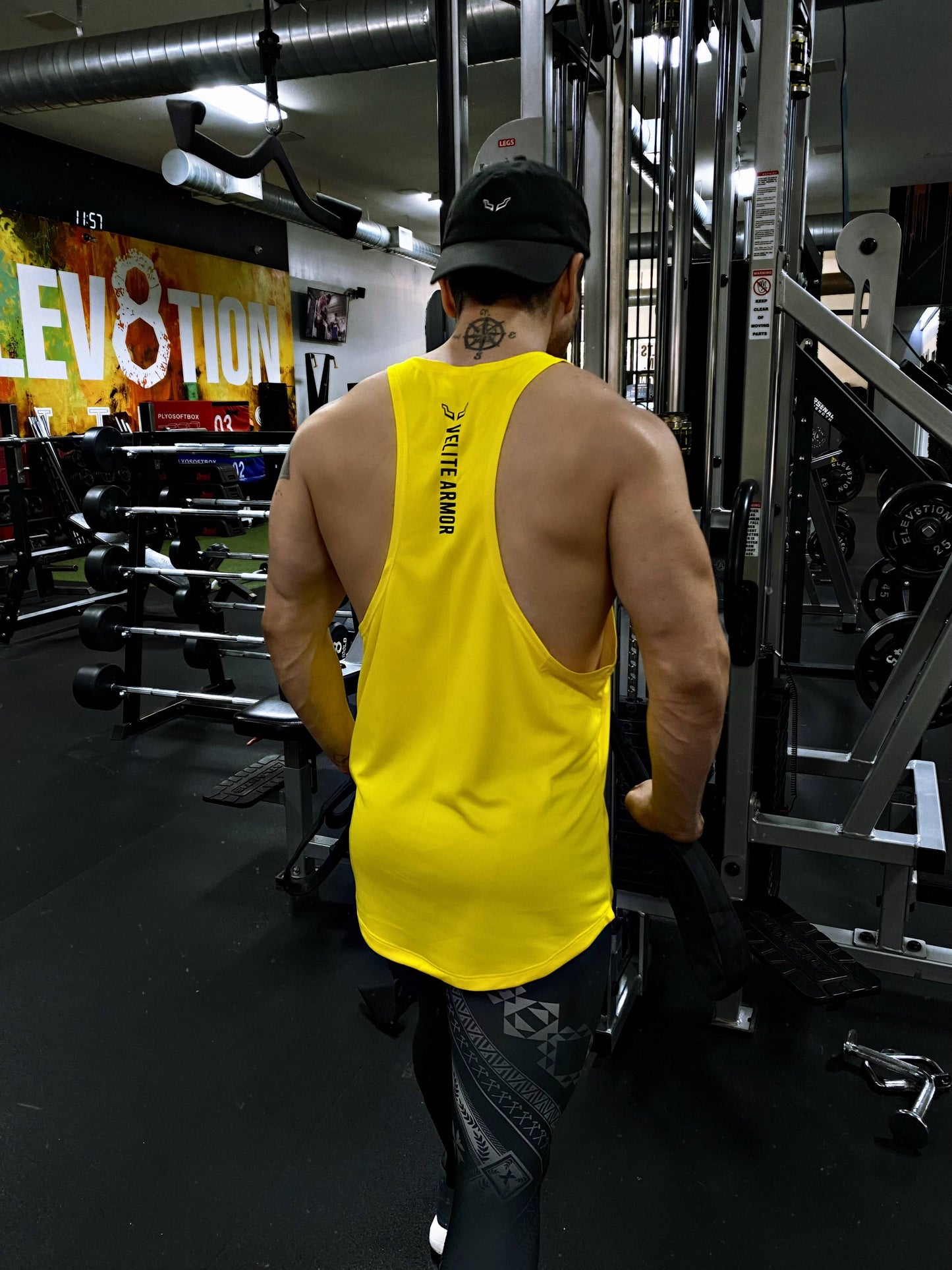 Yellow Booster Athletic Wear tank top by Velite Armor, rear view during cable workout, emphasizing ergonomic fit and color durability.