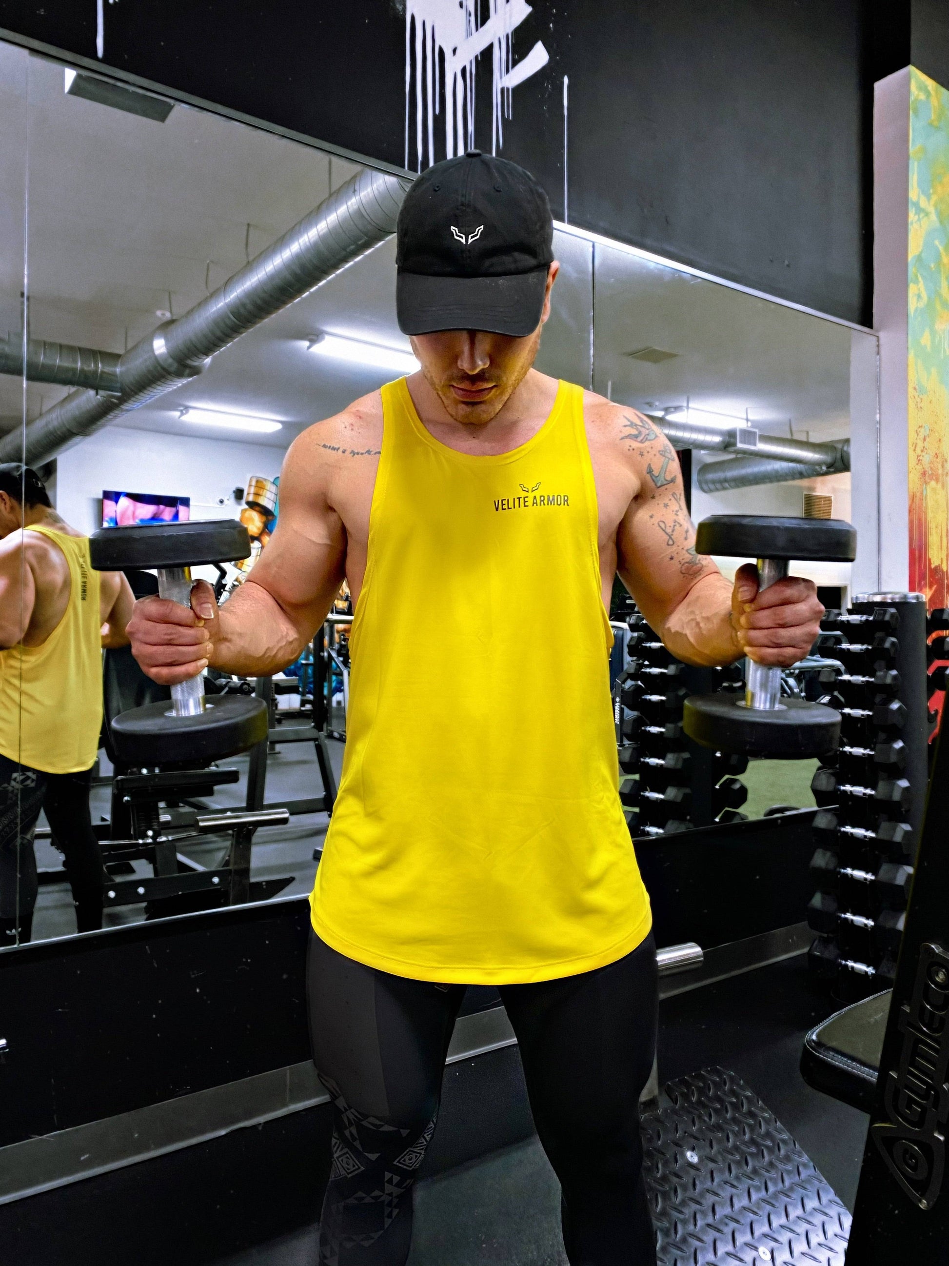 Yellow Booster Athletic Wear tank top by Velite Armor, modeled during dumbbell workout, showcasing advanced durability and moisture control.
